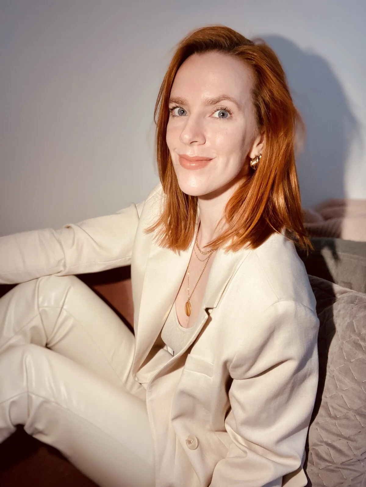 Rosie Rapp sitting in a cream suit, smiling at the camera