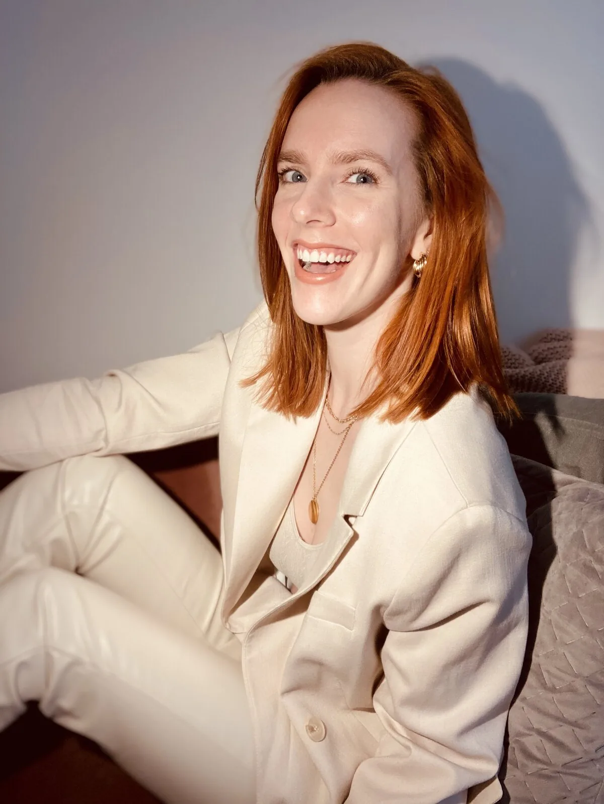 Rosie Rapp laughing in a cream suit