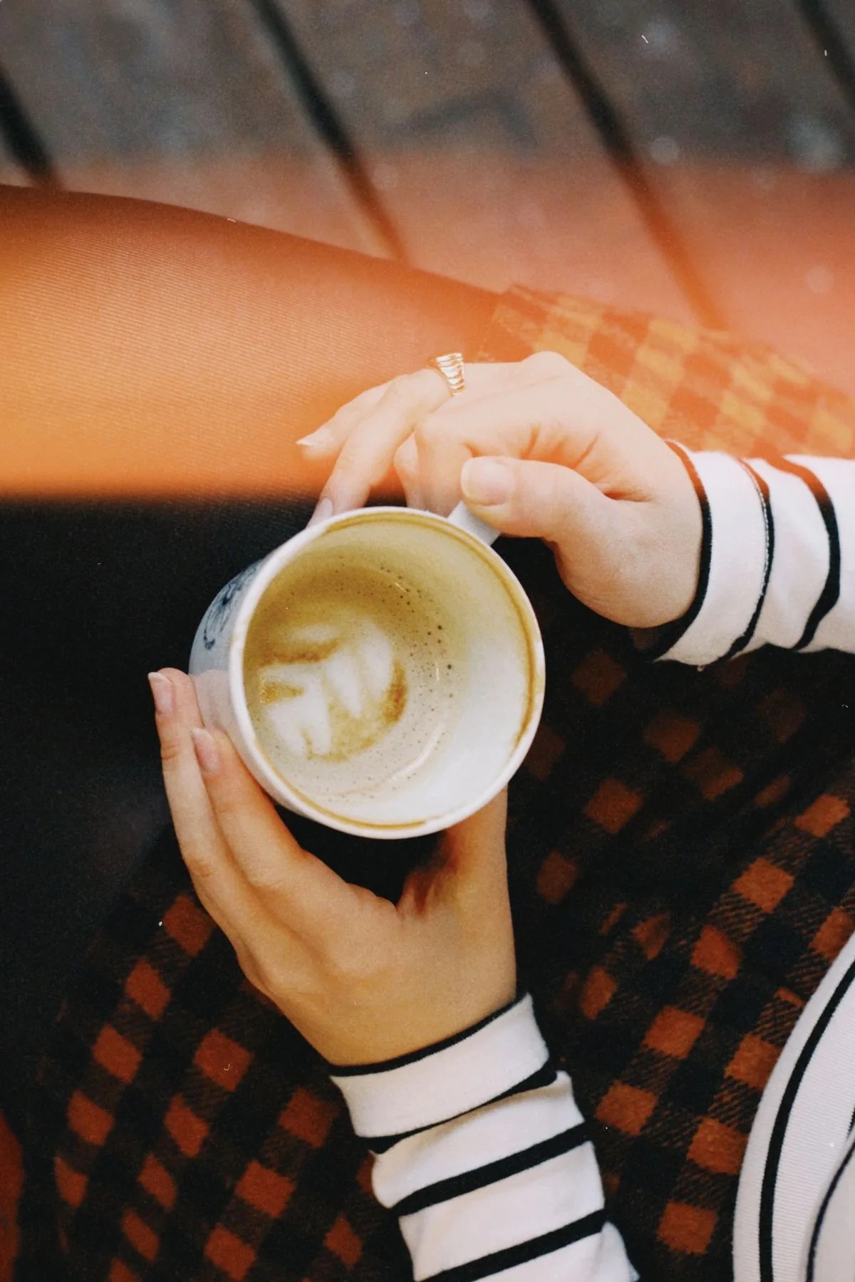 Two hands wrapped around a cup of coffee